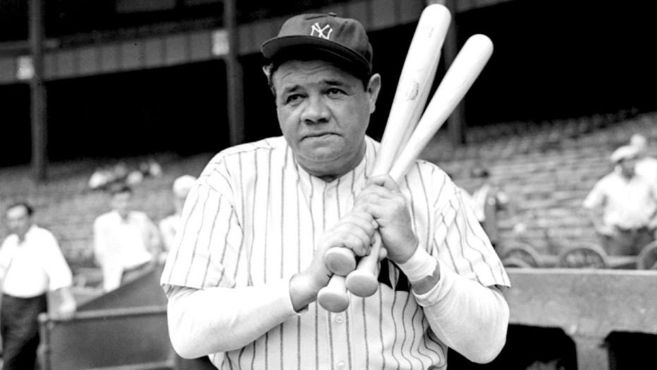 babe ruth posing with bats for the camera