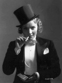 Marlene Dietrich - dressed in a top hat and tuxedo, smoking a cigarette